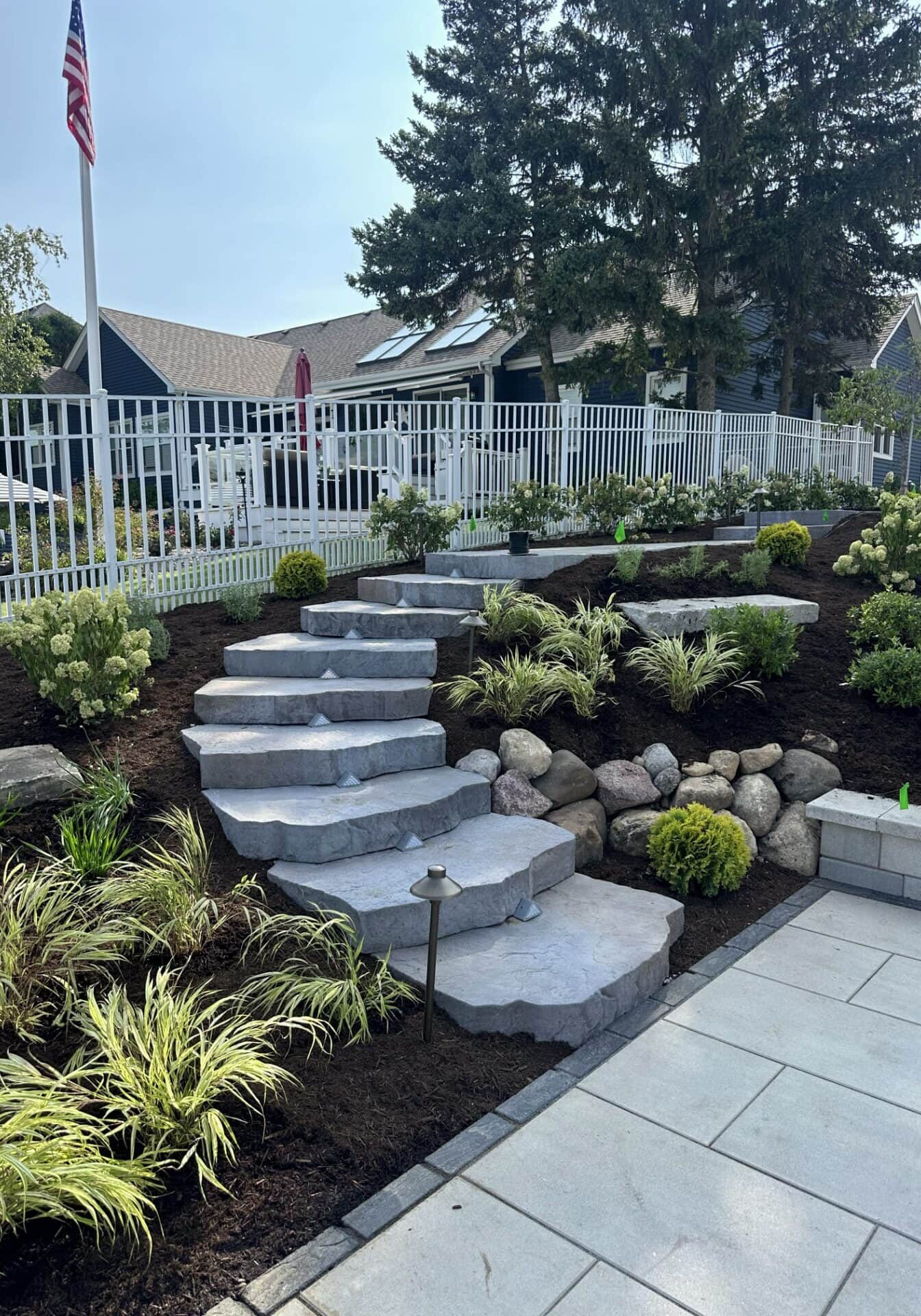 Stone steps in landscaped garden with flagpole.